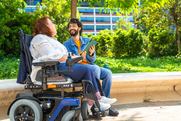 Happy woman in wheelchair smiling and listening to man reading in park