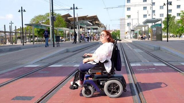 Confident woman in electric wheelchair navigates city tram tracks, showcasing accessible urban infrastructure