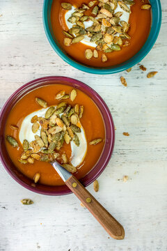 Bowls of pumpkin soup garnished with sour cream and pumpkin seeds 