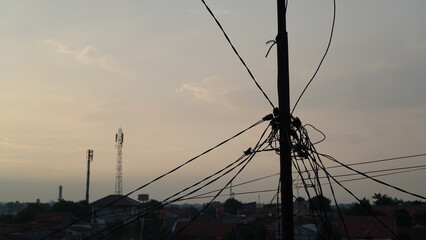 Silhouette of a Utility Pole with Tangled Wires at Sunset