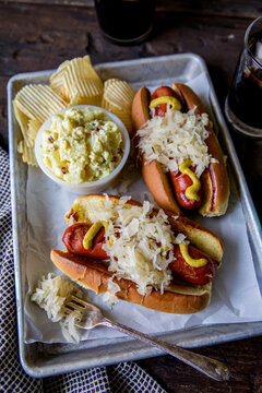 Brats on a bun with sauerkraut mustard and potato salad  