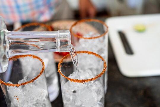 Vodka being poured into a rimmed collins glass for bloody marys 