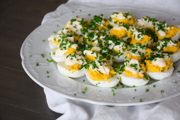 White platter with deviled eggs garnished with chives