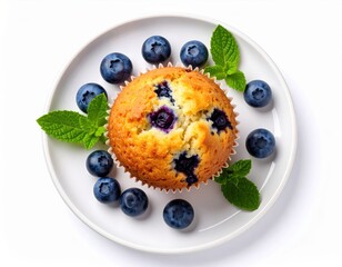 A delicious golden-brown blueberry muffin sits on a white plate surrounded by fresh blueberries and vibrant green mint leaves, a perfect sweet treat for breakfast or dessert.