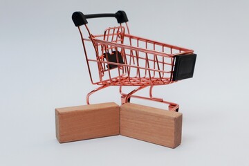 Pink shopping trolley and wooden blocks on white background
