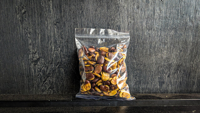 snack in clear plastic packaging on black background - Kacang koro kulit is a snack made from koro beans processed with their skin.