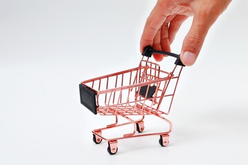 Hand holding pink shopping trolley on white background