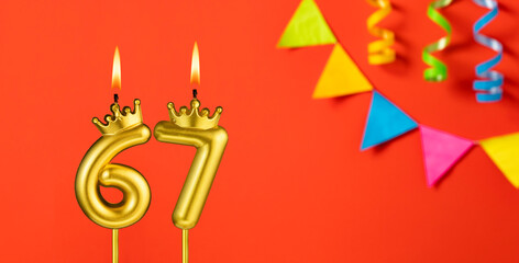 Number 67 candle - Birthday celebration on an orange background with pennants