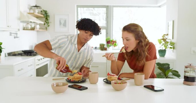 Diverse couple enjoying breakfast with pancakes and syrup in bright modern kitchen, at home