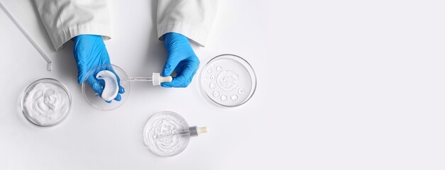 Scientist's hands using glass dropper and Petri dishes with samples on white background with space...