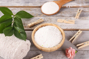 Laundry detergents, clothespins and carnation flower on wooden background