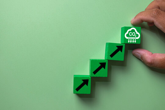 Hand placing a green wooden block with CO2 reduction icon atop ascending arrow blocks. Concept of sustainability goals,net-zero targets,climate change, reduce greenhouse gas emissions,reduce co2.