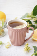 Cup of linden tea with lemon on white background