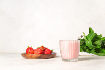 Glass of tasty strawberry smoothie on light background