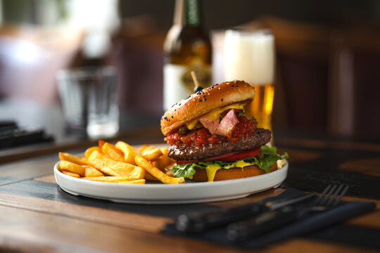delicious beef burger with fresh vegetables, and sesame bun, served with golden fries and beer, ideal for food and restaurant visuals
