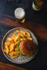 delicious beef burger with fresh vegetables, and sesame bun, served with golden fries and beer, ideal for food and restaurant visuals