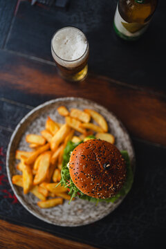 delicious beef burger with fresh vegetables, and sesame bun, served with golden fries and beer, ideal for food and restaurant visuals