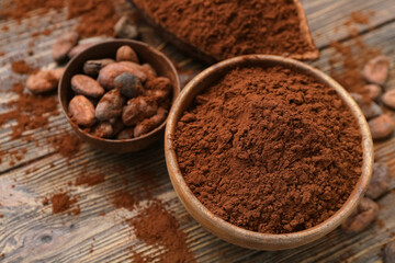 Bowls with cocoa powder and beans on wooden background