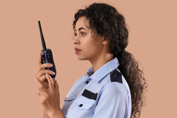 African-American female police officer with radio transmitter on brown background