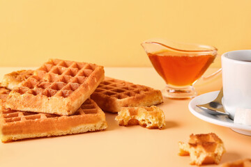 Tasty Belgian waffles with gravy boat of sweet honey and cup of coffee on yellow background