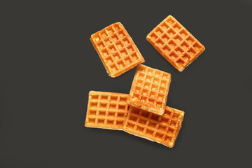 Flying tasty Belgian waffles on black background