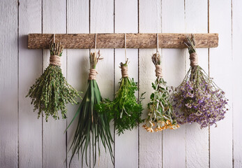 Dried Herbs Hanging on Jute String Above Rustic Wood on white wall