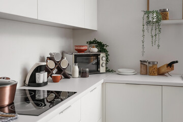 Coffee machine with cups and microwave oven on counter in kitchen
