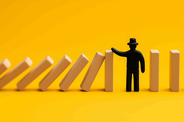 Silhouette of a man making a stop gesture to prevent wooden dominos from collapsing