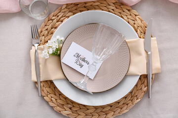 Table setting for Mother's Day celebration with greeting card and beautiful flowers, closeup