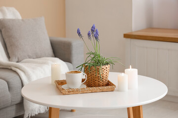 Beautiful Muscari flowers, cup of coffee and burning candles on light table in room