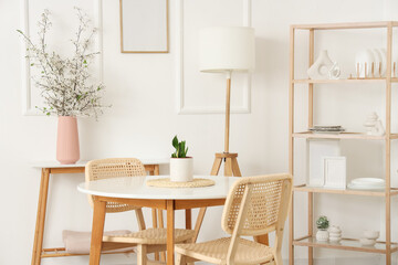 Interior of kitchen with shelving unit and blooming branches in vase on table