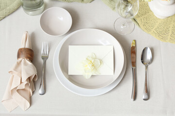 Elegant table setting with beautiful narcissus flower and envelope in bowl, closeup