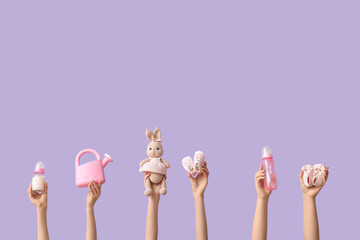 Hands holding baby accessories on lilac background