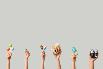 Hands holding baby accessories on grey background