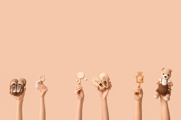 Hands holding baby accessories on beige background