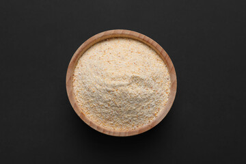 Aromatic garlic powder in bowl on dark table, top view