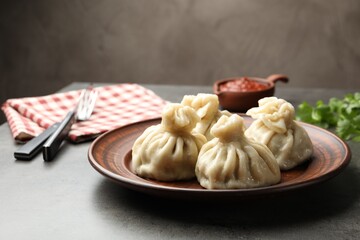 Delicious khinkali served with sauce on grey table, closeup