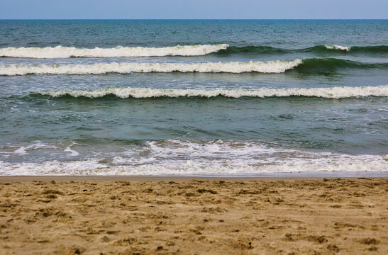A nice closeup landscape in summer of a brown trampled sandy beach with bubbly emerald-green waves in the ocean at Carolina Beach in Wilmington, North Carolina in the U.S. - Powered by Adobe