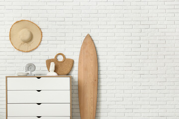 Interior of stylish room with dresser, summer decor and surfboard