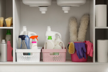 Open drawer with baskets of different cleaning supplies, brushes, rubber gloves and pp-dusters in...