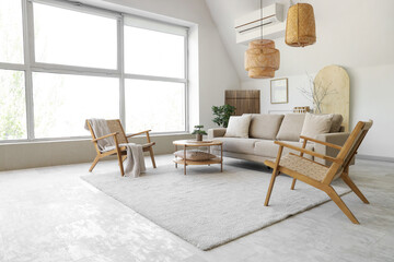 Interior of stylish living room with cozy grey sofa, coffee table and armchairs