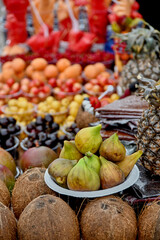 Vibrant market display featuring variety of fresh fruits, including figs, coconuts, pineapples, apricots, cherries, and red currants, Tklapi (Georgian fruit leather). Selective focus