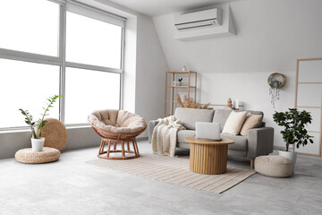 Interior of stylish living room with cozy grey sofa, armchair and laptop on coffee table