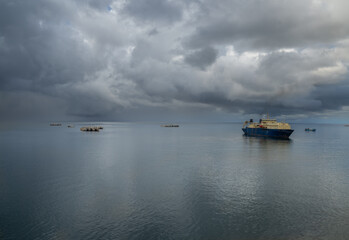 Ship anchored in calm waters under gray sky