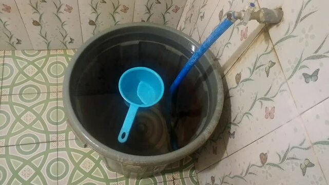 Bathroom bucket with blue dipper and plastic water tap
