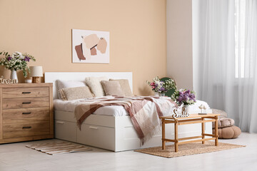 Interior of stylish spring bedroom with bed, mirror, commode and beautiful flowers bouquets in...