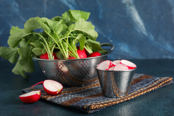 Small bucket and collander with ripe radish on blue background