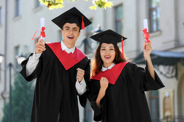 Couple of happy students with diplomas on their graduation day