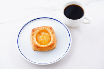 Delicious apple danish with a cup of fresh coffee on the white plate
