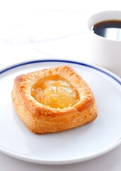 Delicious apple danish with a cup of fresh coffee on the white plate
